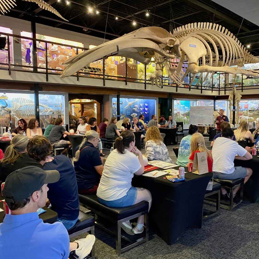 People attending forensic night under a large whale skeleton display.